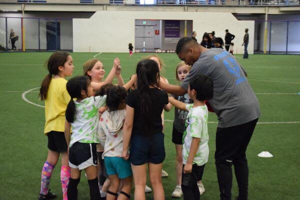 Soccer trainer and kid soccer players giving a high-five